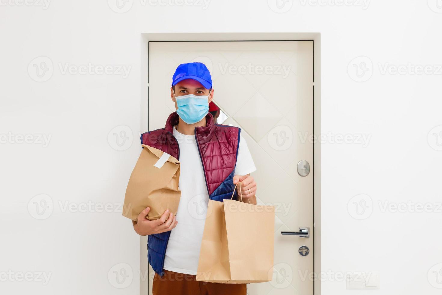 entrega hombre participación papel bolso con comida en blanco fondo, comida entrega hombre en protector máscara foto