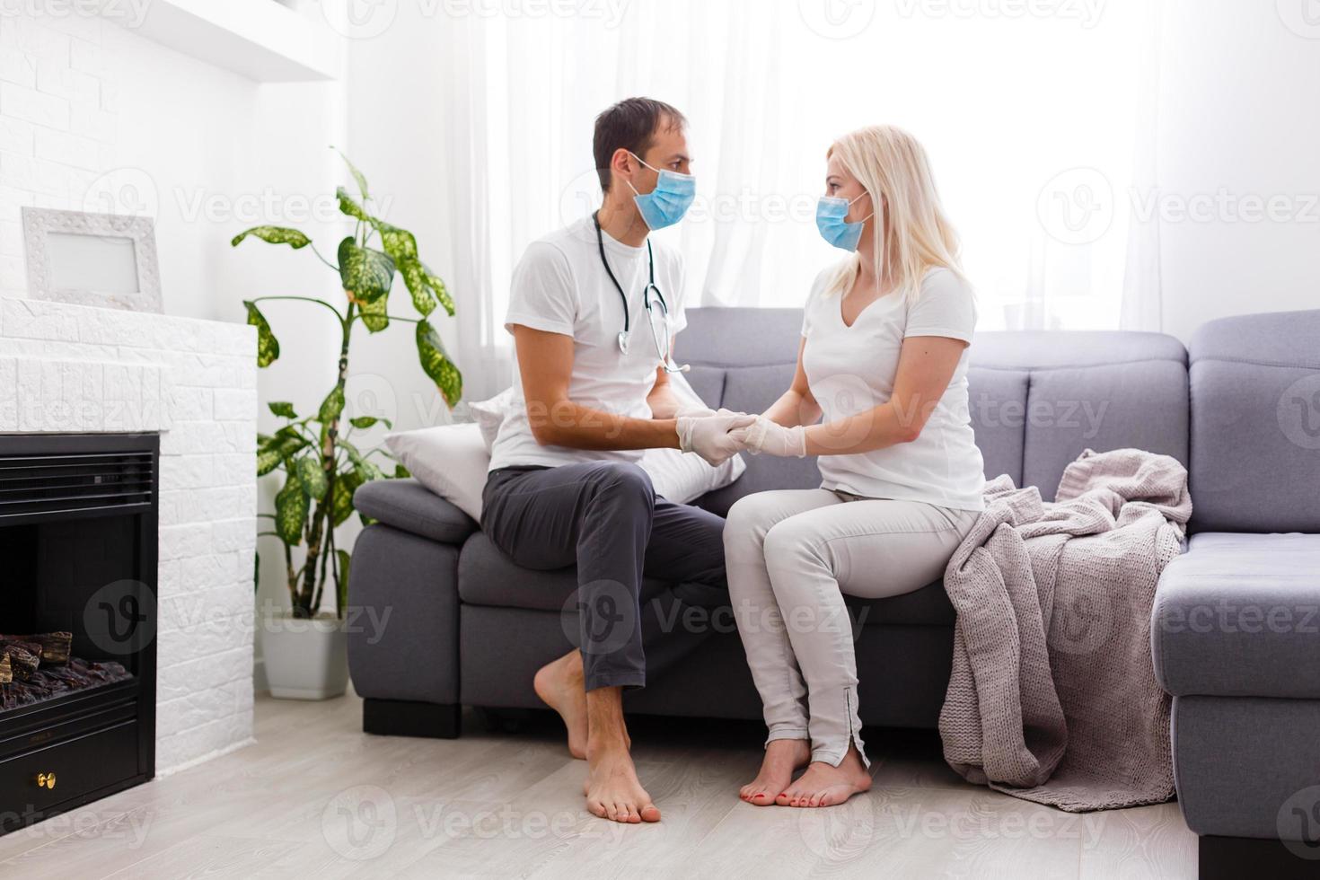 Coronavirus. A couple sitting on a sofa on a quarantine at home Couple at home on the couch looking each other, both wear masks because of avoiding contagion. Stay at home. Romantic. photo