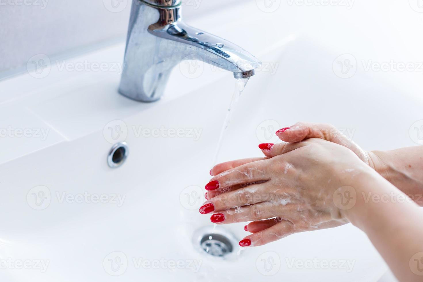 Woman washing hands with soap in bathroom photo