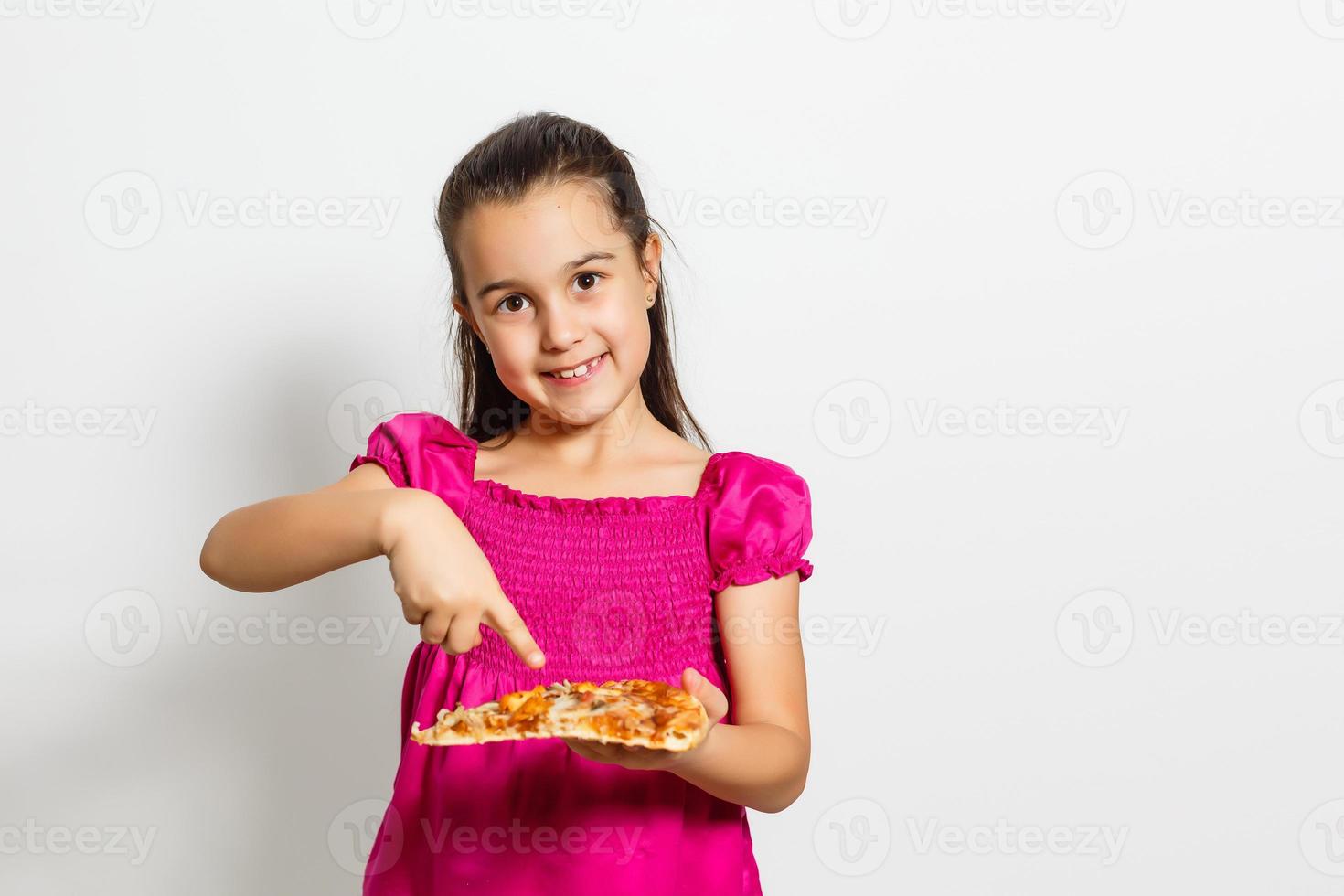 Cute little Indian Asian girl child eating tasty Pizza. Standing isolated over white background. photo