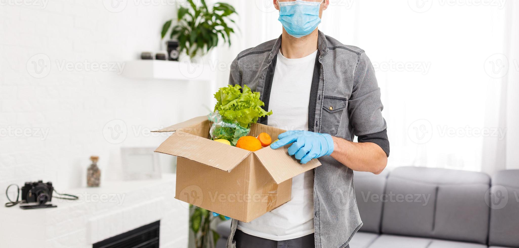 Man wearing medical face mask Disassembles food bags at home. quarantine. health concept. Corona Virus. order of products online. Delivering products to home. Delivery service photo