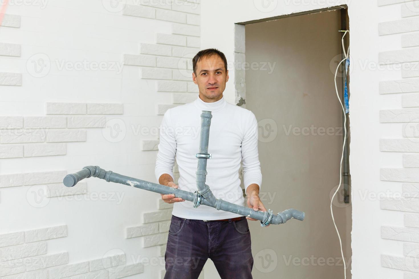 Young plumber in uniform holding pvc pipe isolated on white background photo