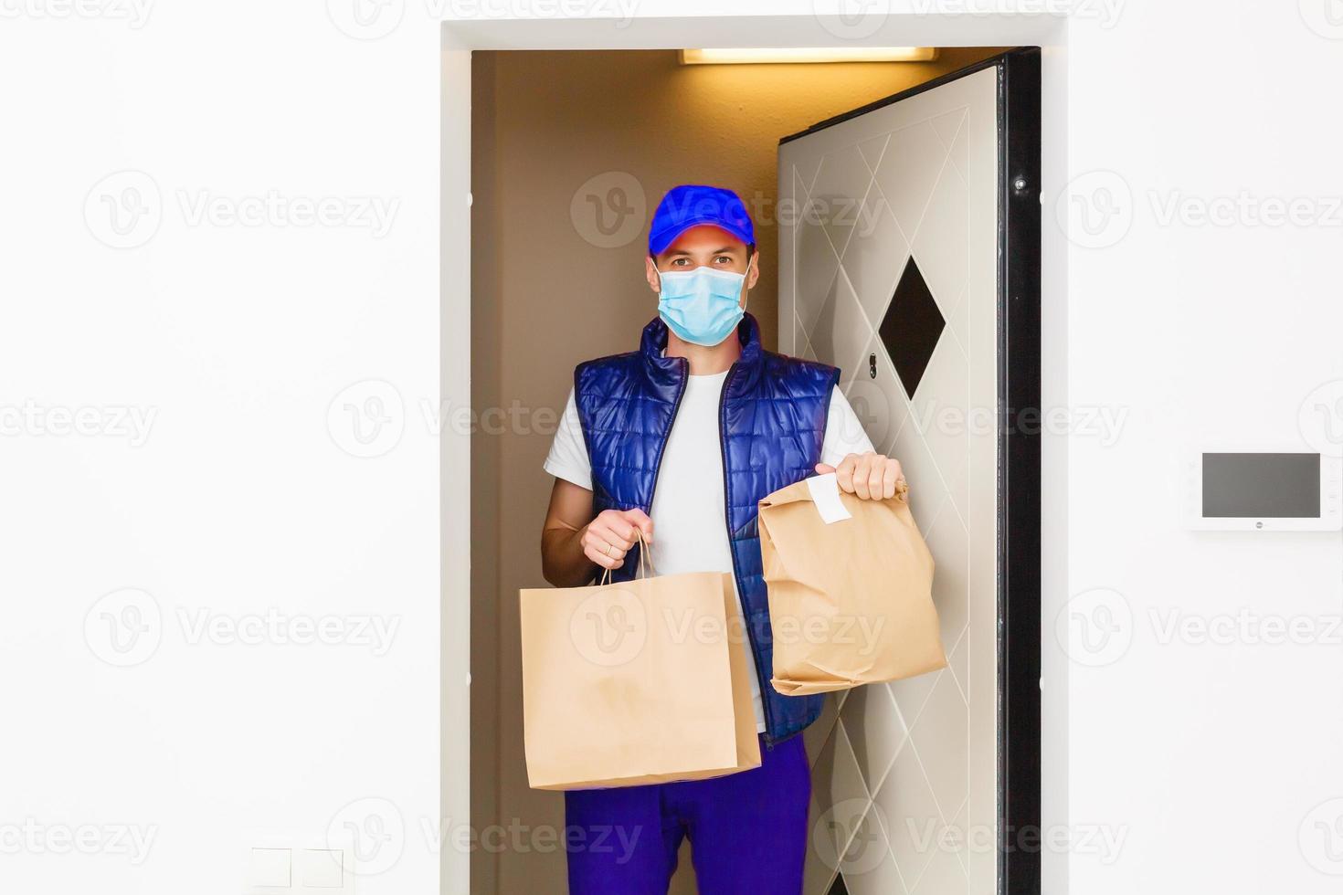 Delivery man holding paper bag with food on white background, food delivery man in protective mask photo