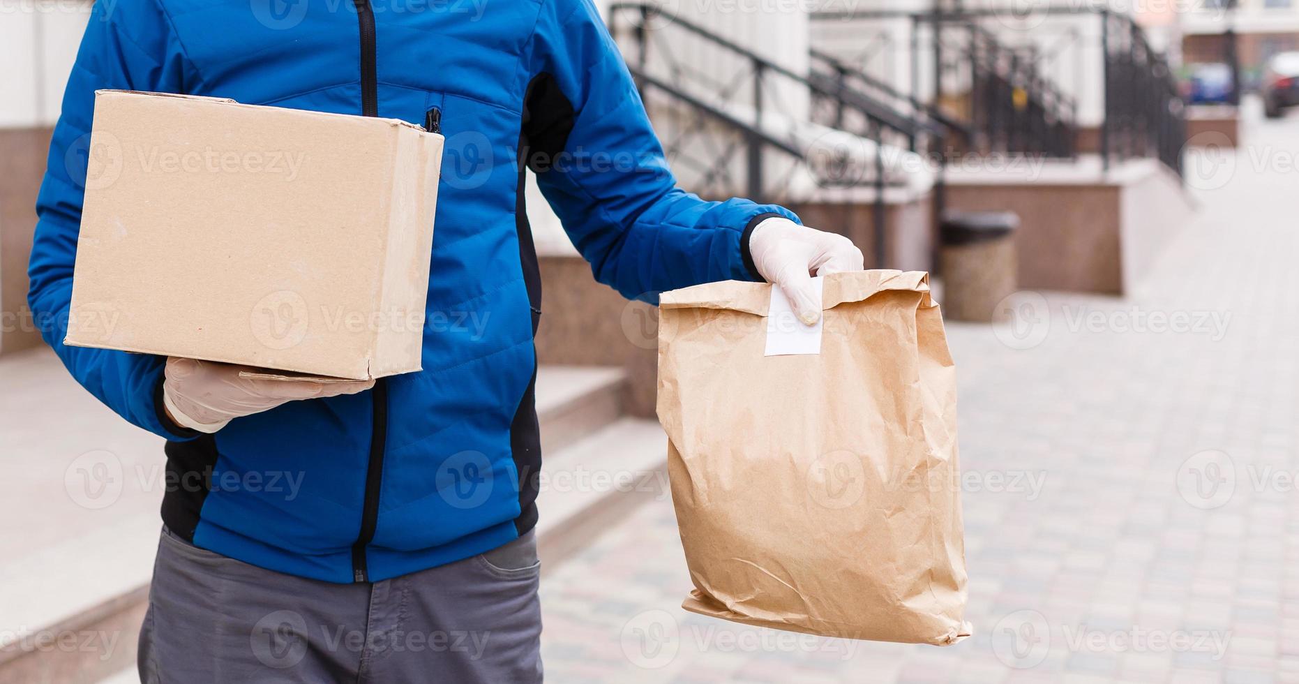 Courier in protective mask and medical gloves delivers takeaway food. Delivery service under quarantine, disease outbreak, coronavirus covid-19 pandemic conditions. photo