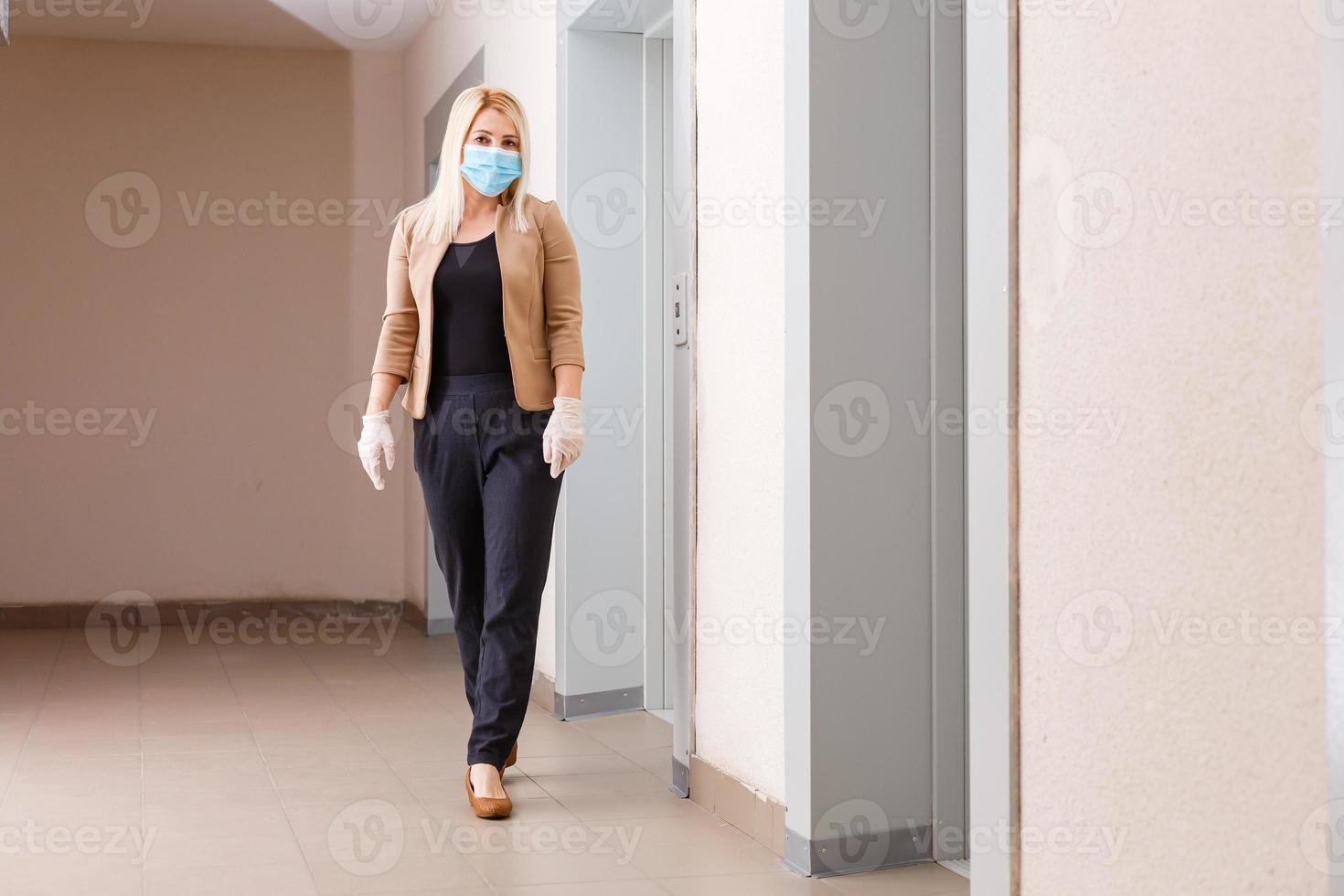 Young woman with medical mask in the elevator of an apartment building photo