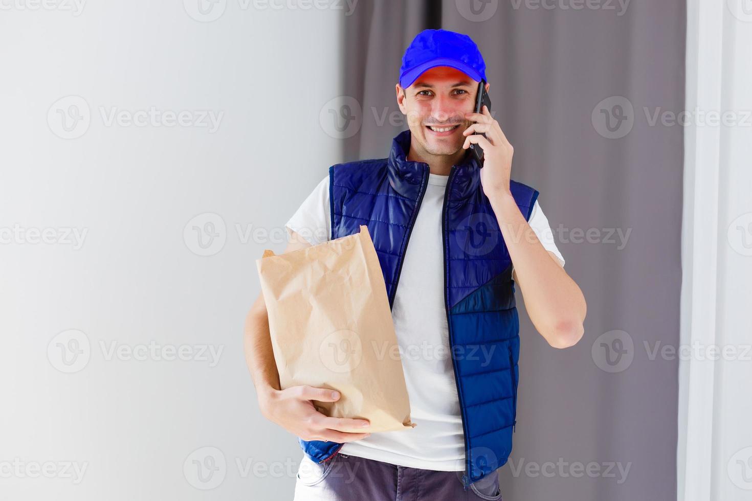 Paper pocket and food containers in hands of a smiling deliveryman. Quality service of a restaurant. photo