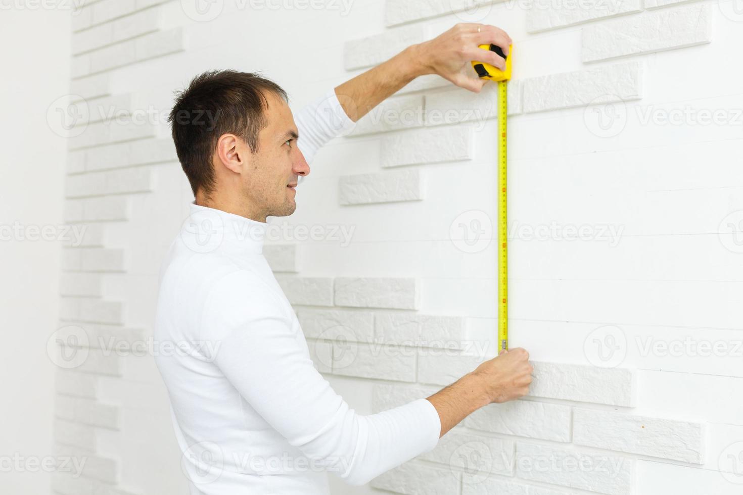 architecture and home renovation concept - male architect measuring wall with flexible ruler photo