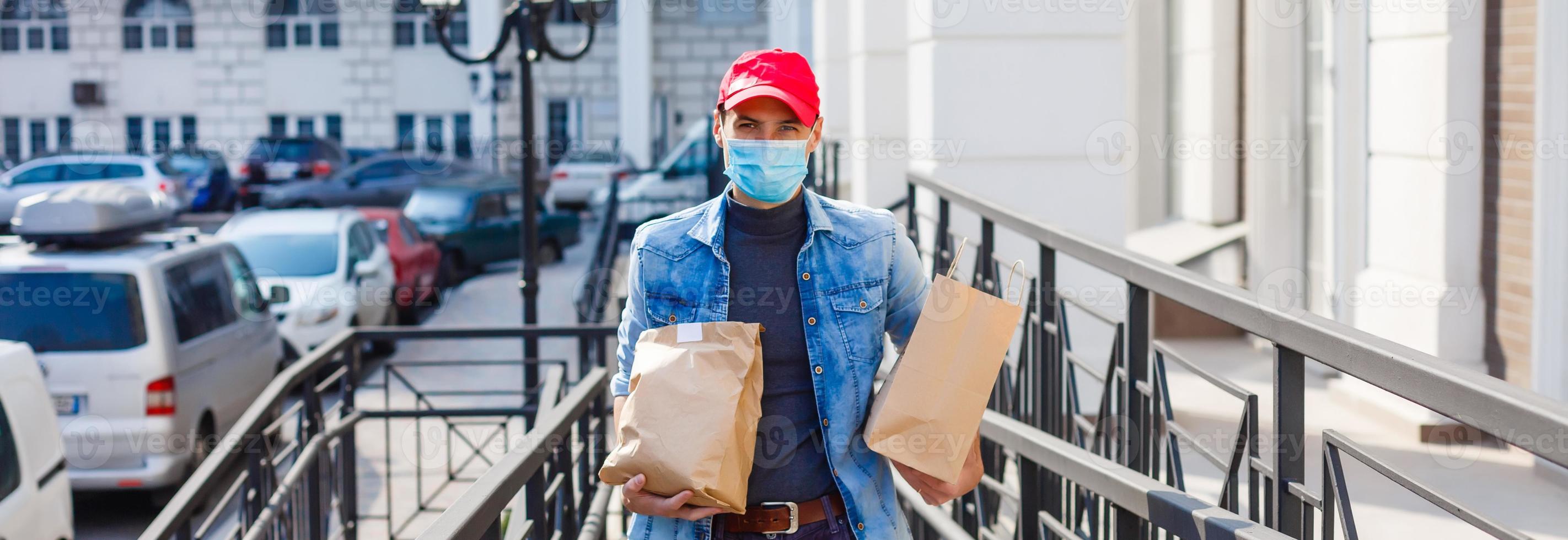 delivery, mail and people concept - man in a protective mask delivering coffee and food in disposable paper bag to customer home photo