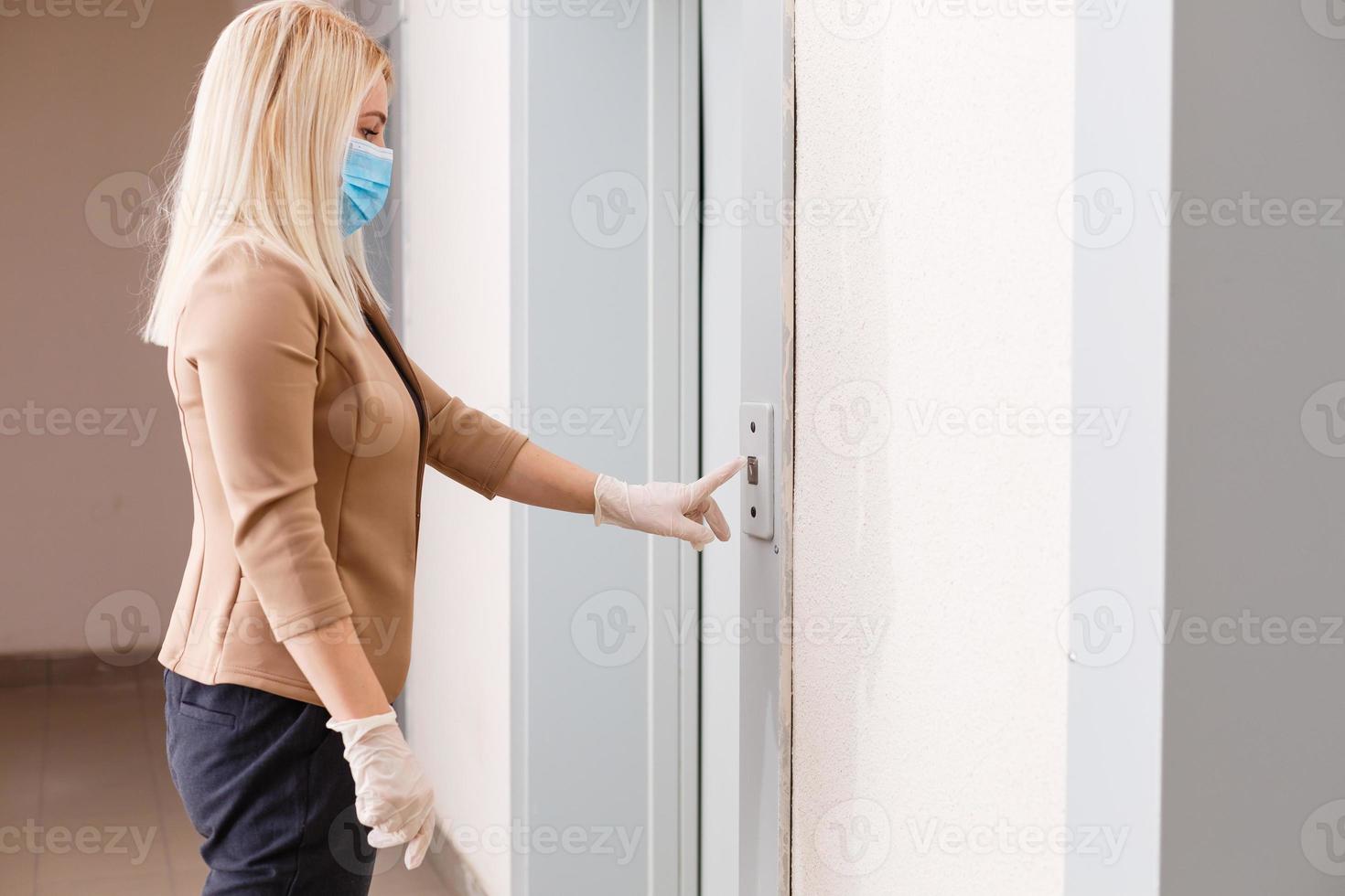 Young woman with medical mask in the elevator of an apartment building photo