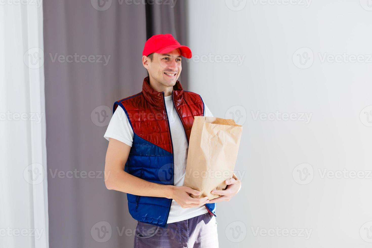 Paper pocket and food containers in hands of a smiling deliveryman. Quality service of a restaurant. photo