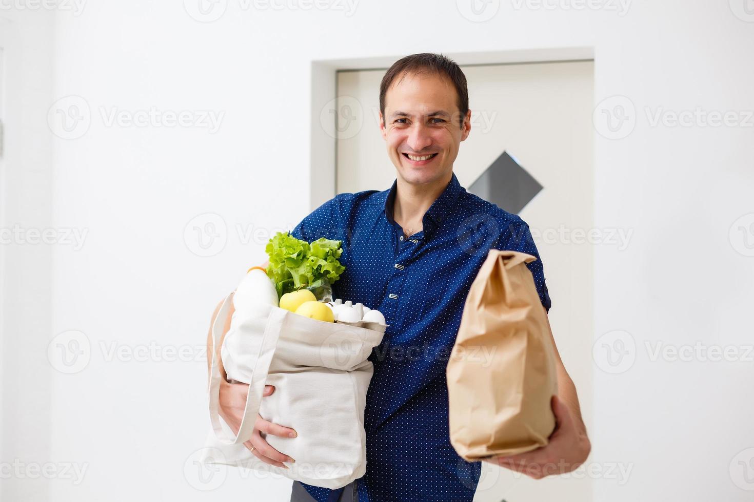 concepto de entrega, correo y personas - hombre feliz entregando comida en una bolsa de papel desechable a la casa del cliente foto