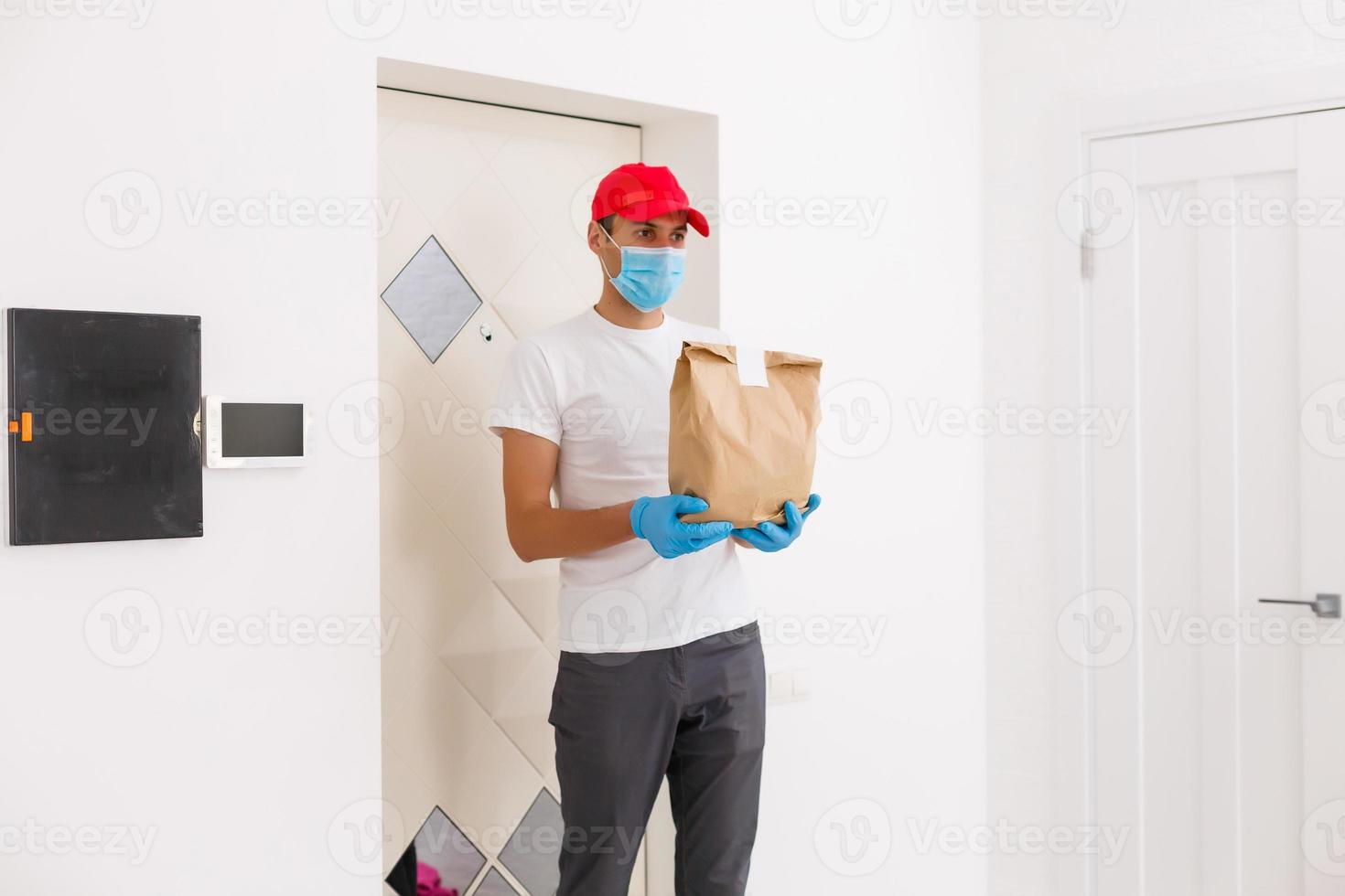 Courier in protective mask delivers parcel, customer in medical gloves receives box. Delivery service under quarantine, disease outbreak, coronavirus covid-19 pandemic conditions. photo