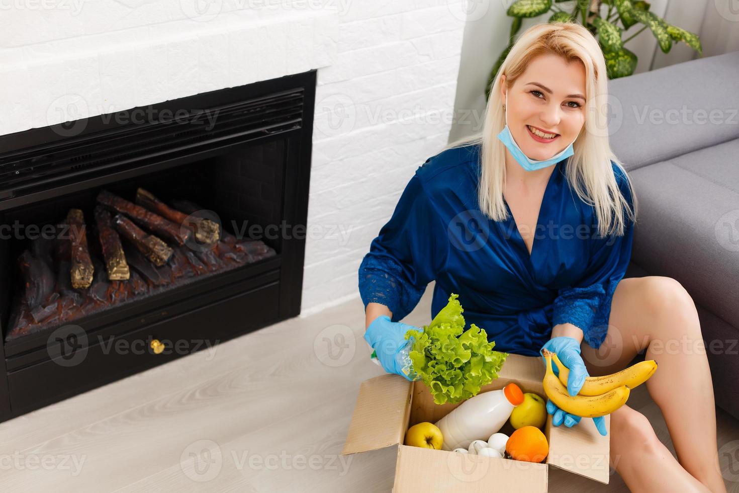 mujer vistiendo médico cara máscara desmonta comida pantalones a hogar en el cocina. cuarentena. salud concepto. corona virus. orden de productos en línea. entregando productos a hogar foto