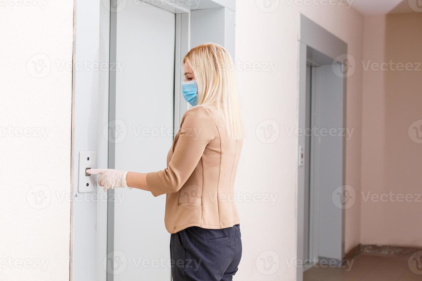 Young woman with medical mask in the elevator of an apartment building photo