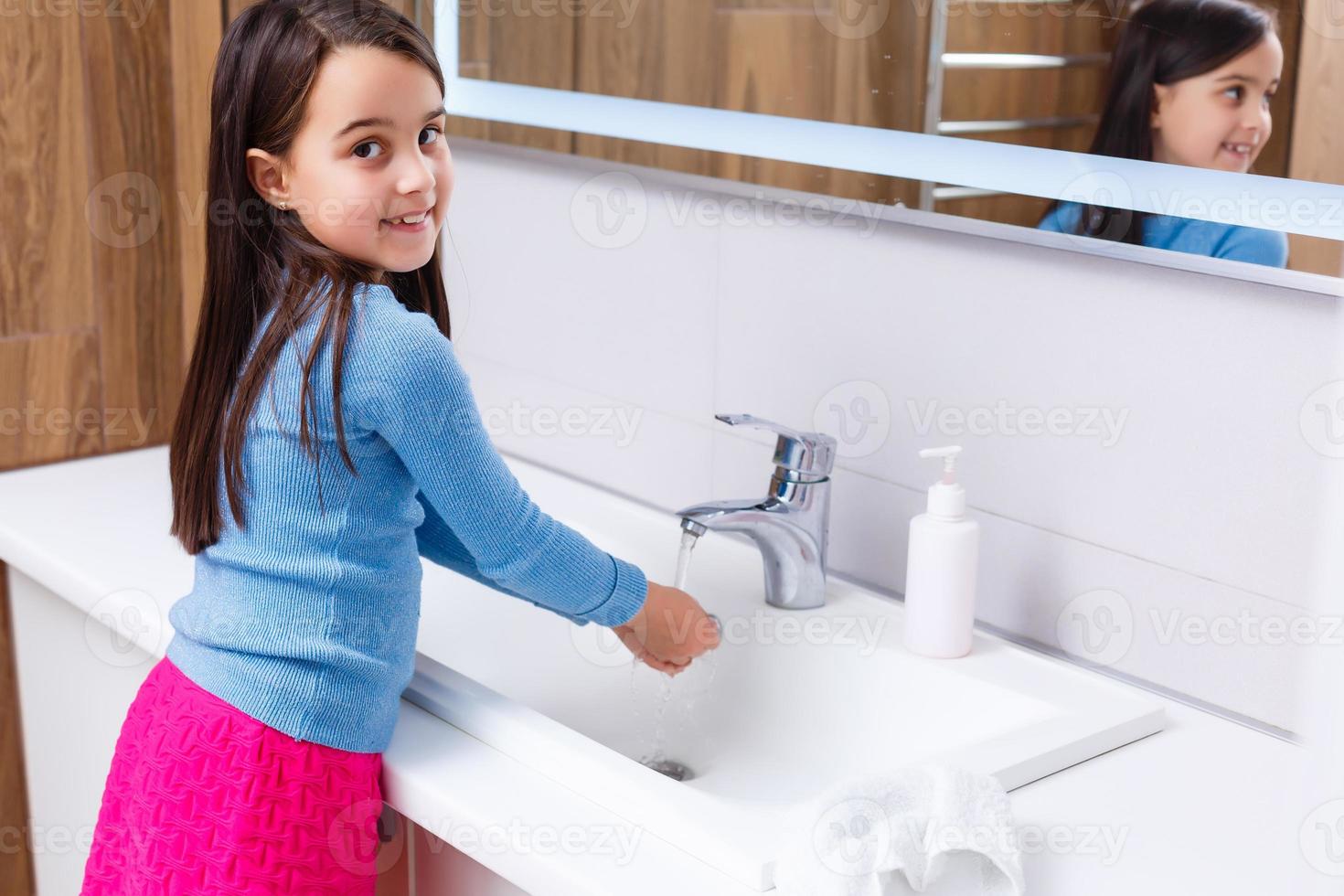 Little girl is washing her hands in the bathroom photo