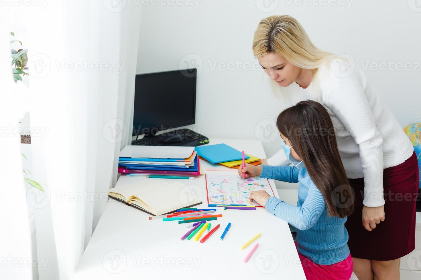 mother and daughter in protective mask do homework at distance home schooling, quarantine photo