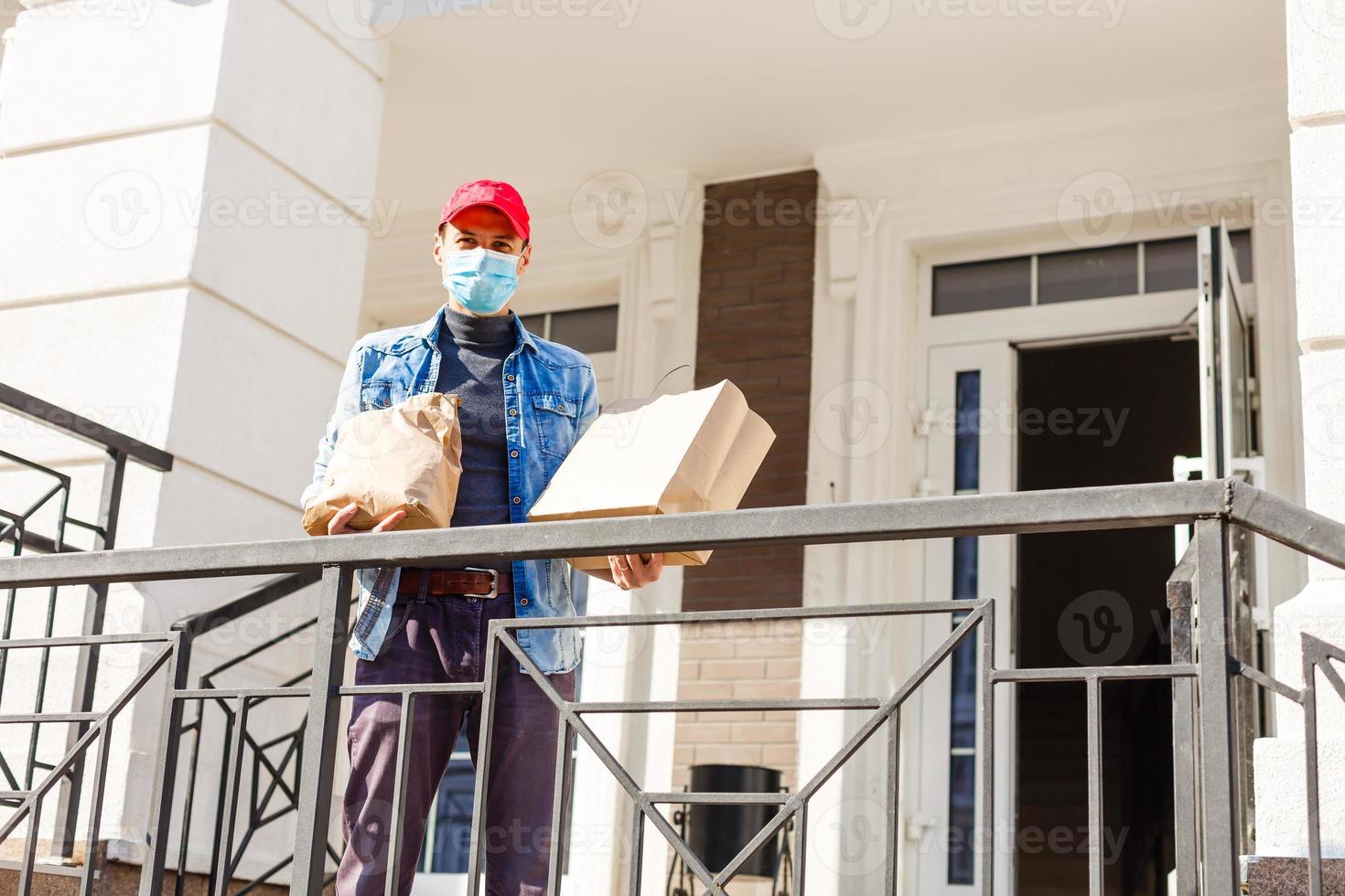 food delivery man with bags in a protective mask on his face photo