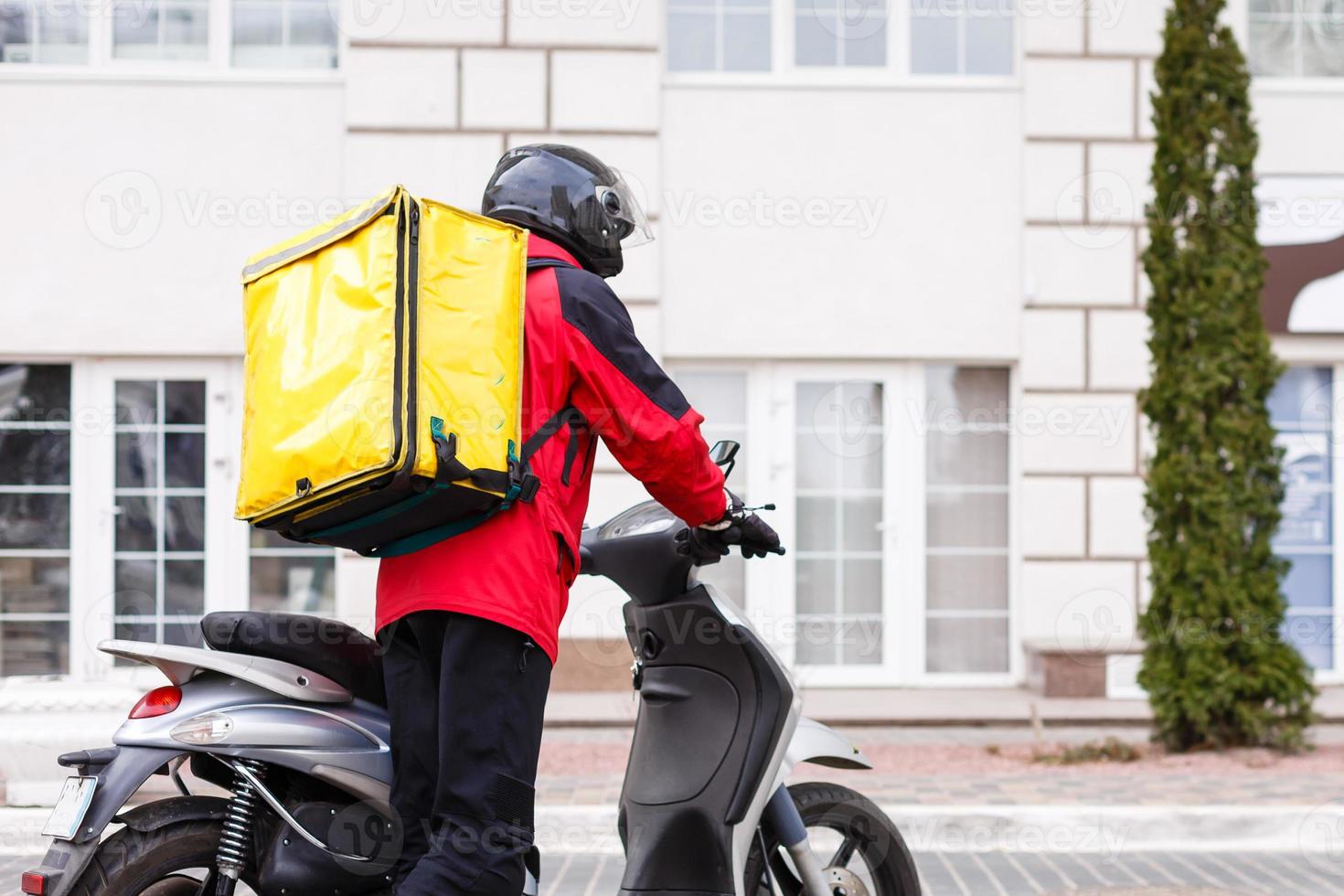 Contactless food delivery to customers home. Delivery service worker with thermal backpack quick delivering food at doorstep in quarantine from restaurant, supermarket or cafe . Online ordering food photo