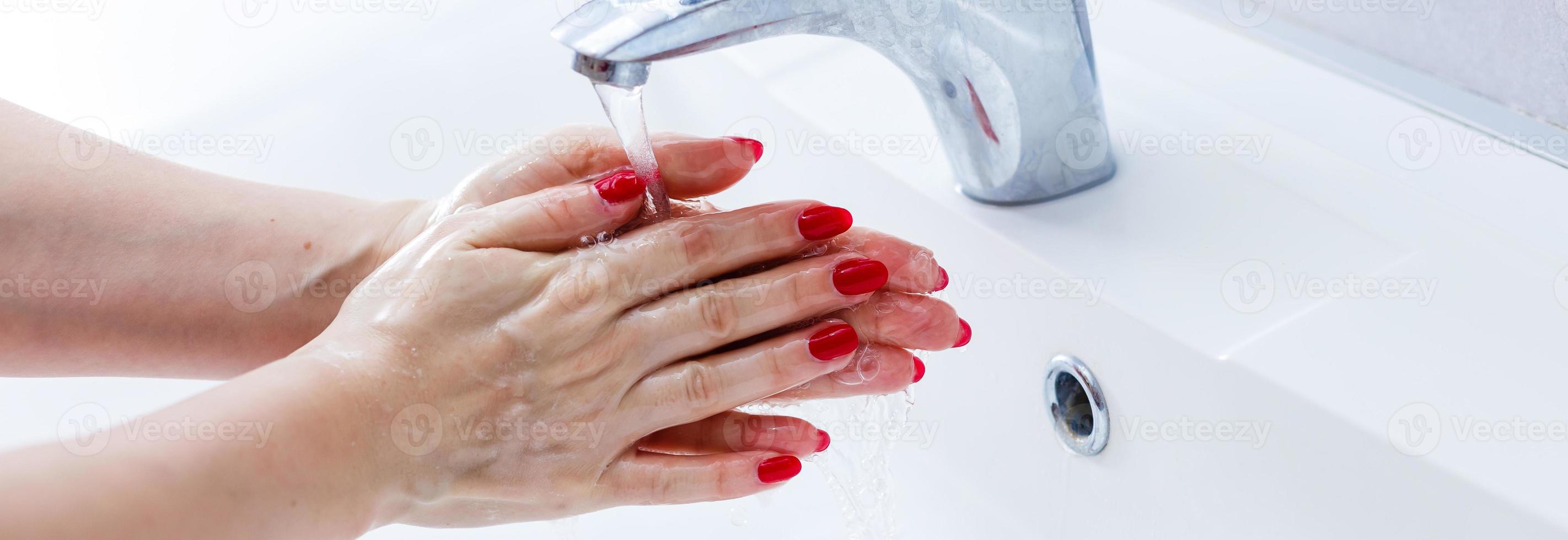 Washing hands in a public restroom focus on the tap, hands in motion photo