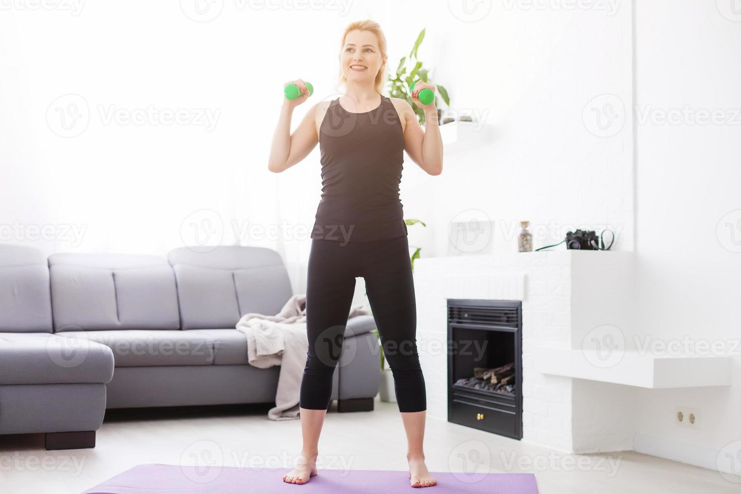 a thin European girl doing stretching exercises at home on a yoga mat, rays of light shine from the window. flare. quarantine sport. photo