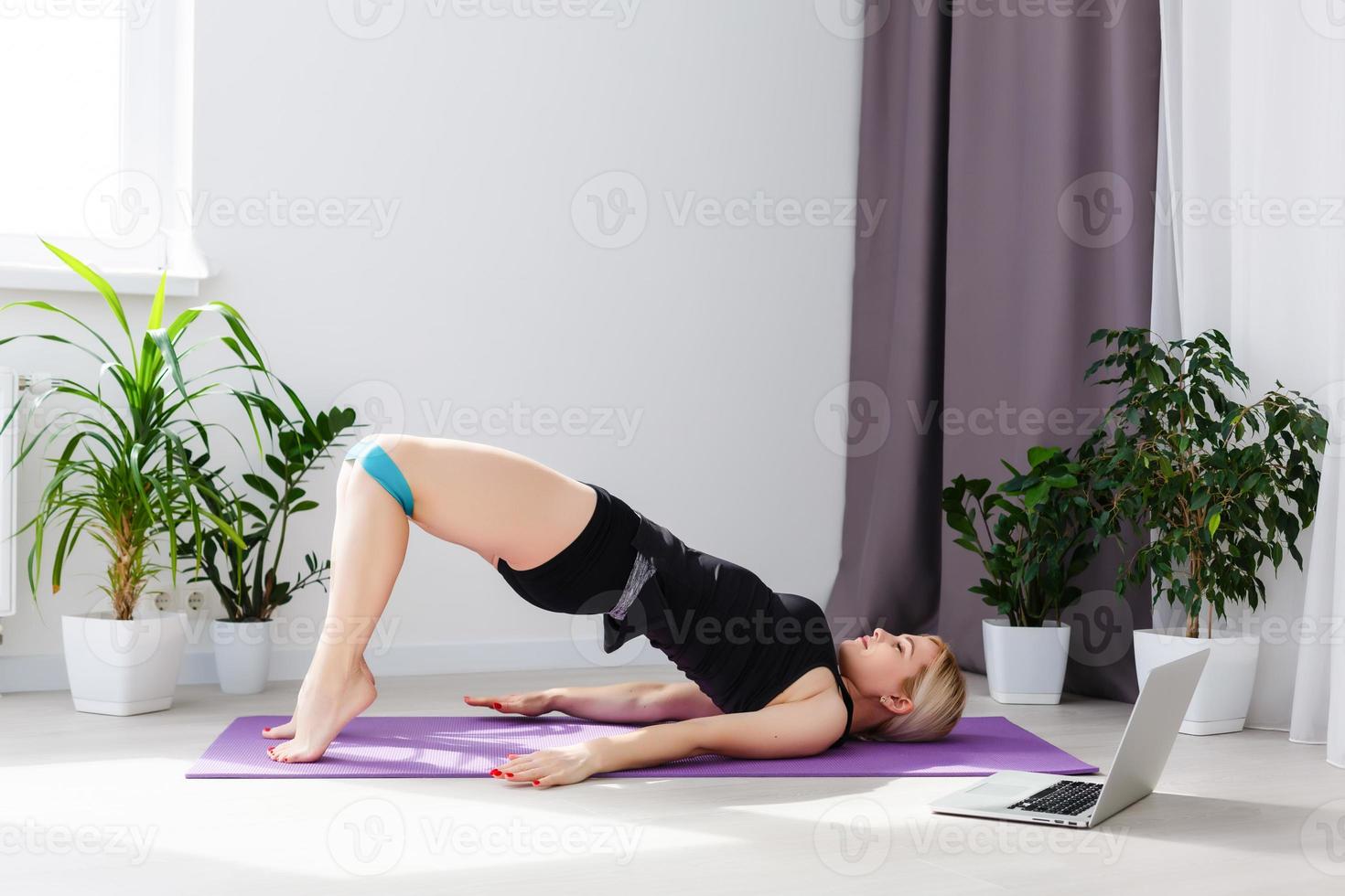 alone girl doing yoga exercises online on laptop on the floor in the light room, stay home safe world. photo