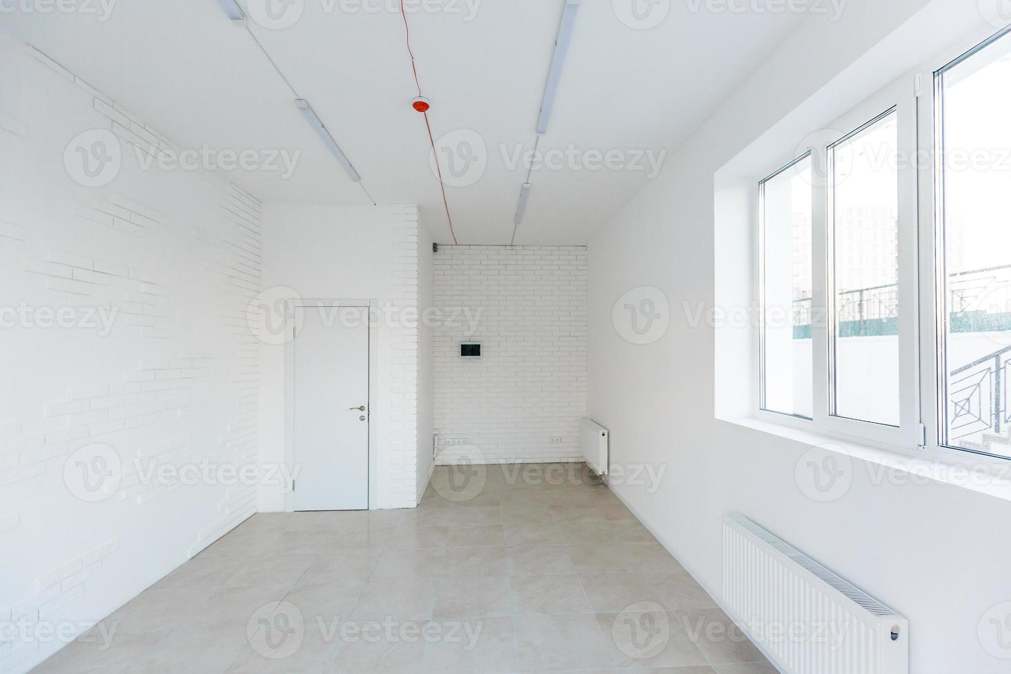 Light room with window and heating battery. Wall is of white plaster, has several outlets. Professional installation of electrical sockets, wires and switches. Connecting the light in flat or office photo
