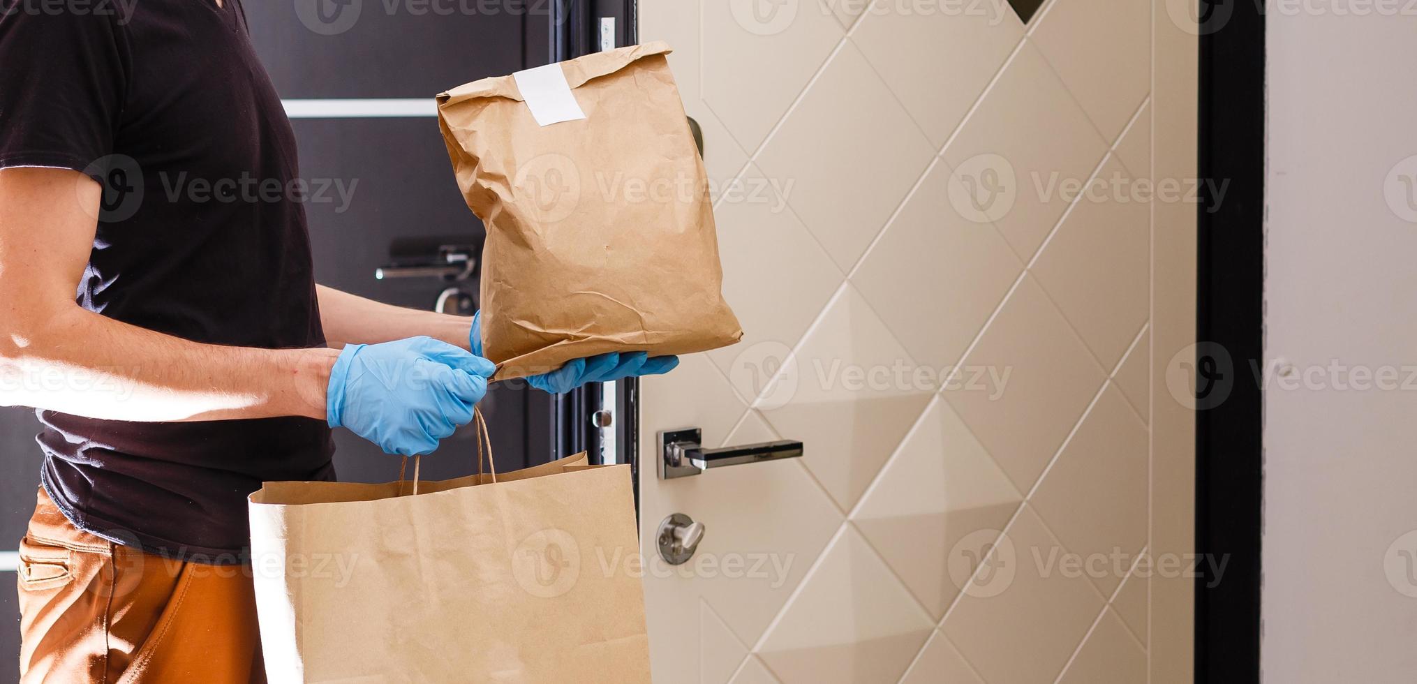 Courier in protective mask and medical gloves delivers takeaway food. Delivery service under quarantine, disease outbreak, coronavirus covid-19 pandemic conditions. photo