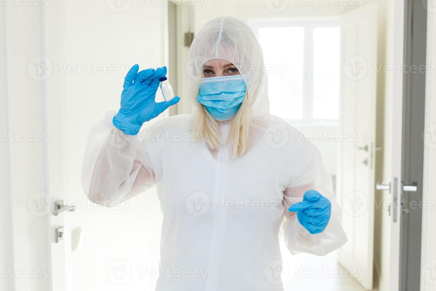 Researcher in hazmat protective suit examining a test tube in the chemical lab. photo
