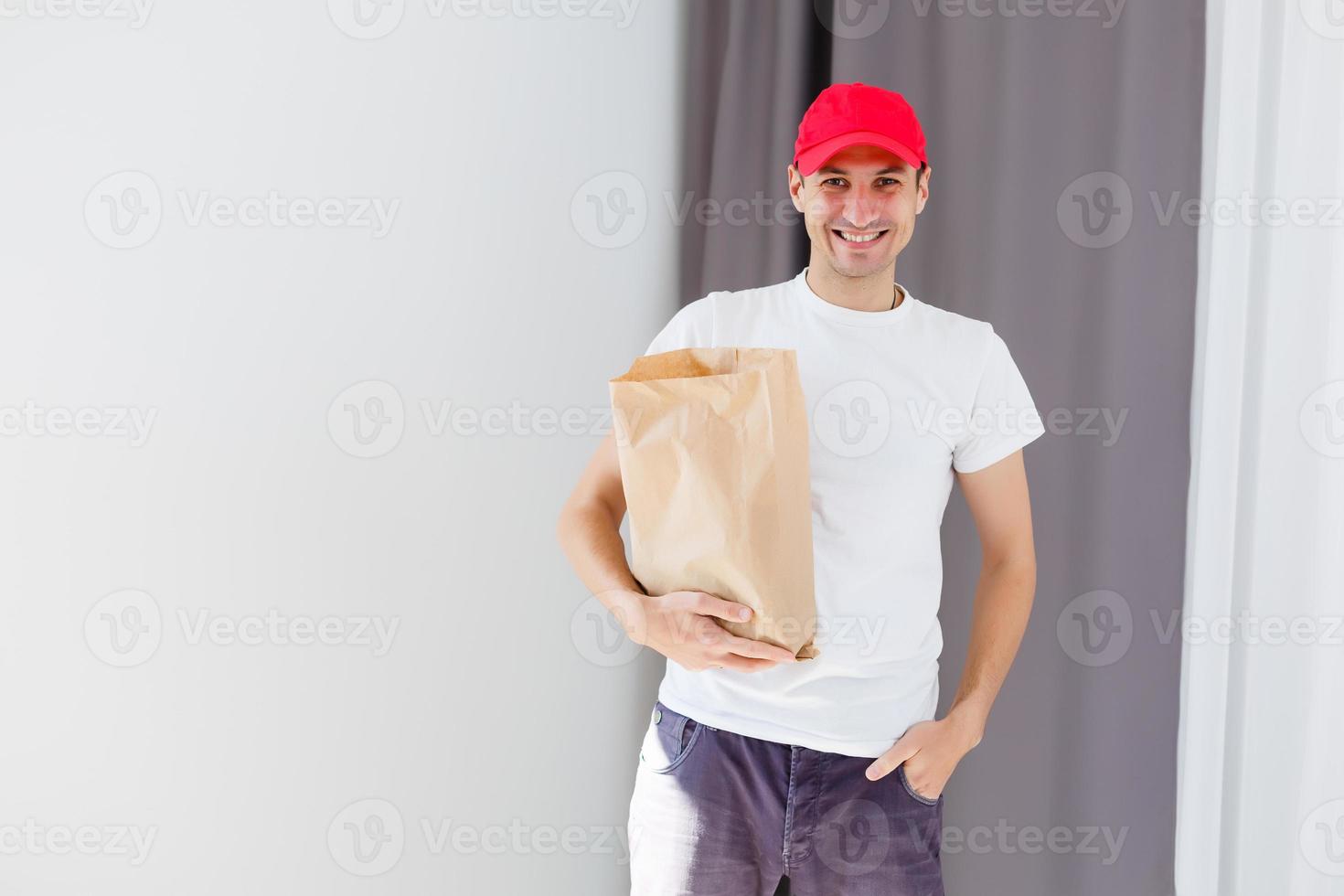 Paper pocket and food containers in hands of a smiling deliveryman. Quality service of a restaurant. photo