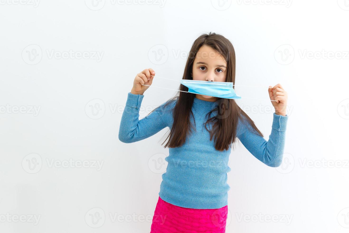 Masked child - protection against influenza virus. Little Caucasian girl wearing mask for protect photo