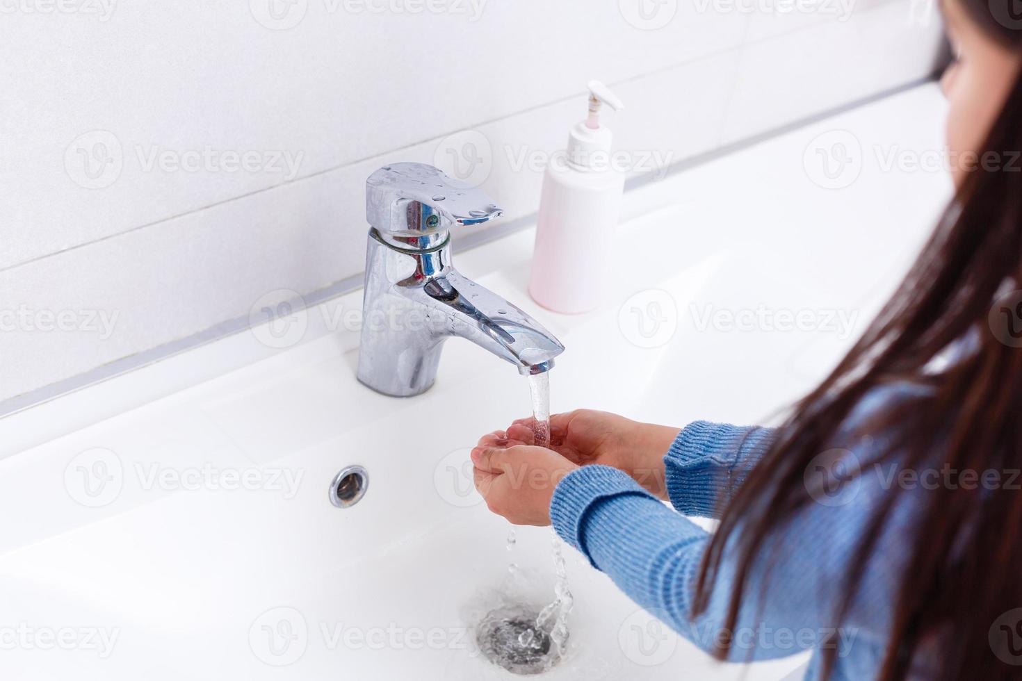 Cute girl washing hands in bathroom photo