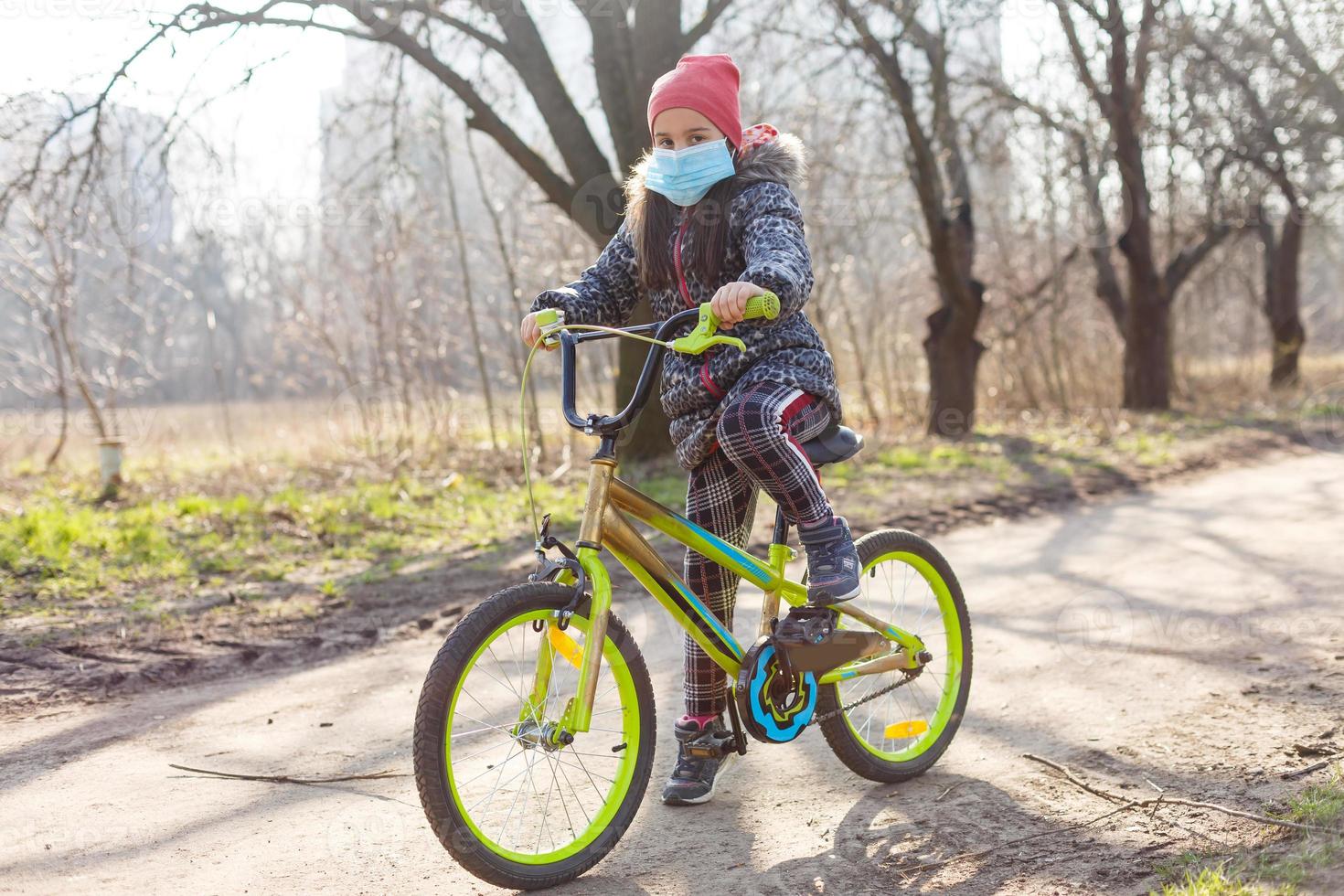 7 7 años antiguo contento pequeño niña niño paseo bicicleta en el parque a hogar y vistiendo proteccion máscara para proteger pm2.5 y coronavirus covid-19 pandemia virus sintomas.deporte ejercicio para salud. foto