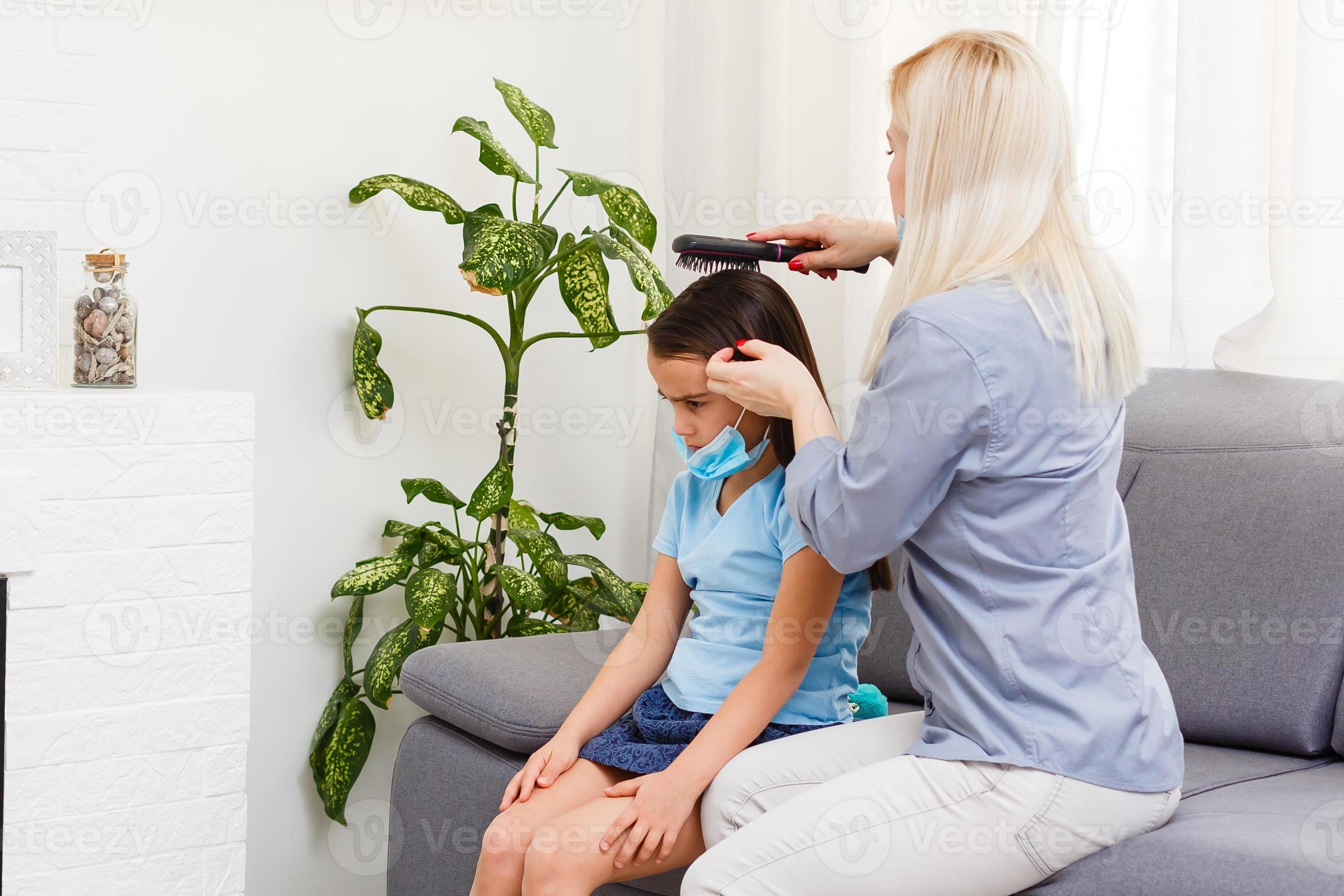 Beautiful mother braiding hair of her daughter in the kitchen. Cute