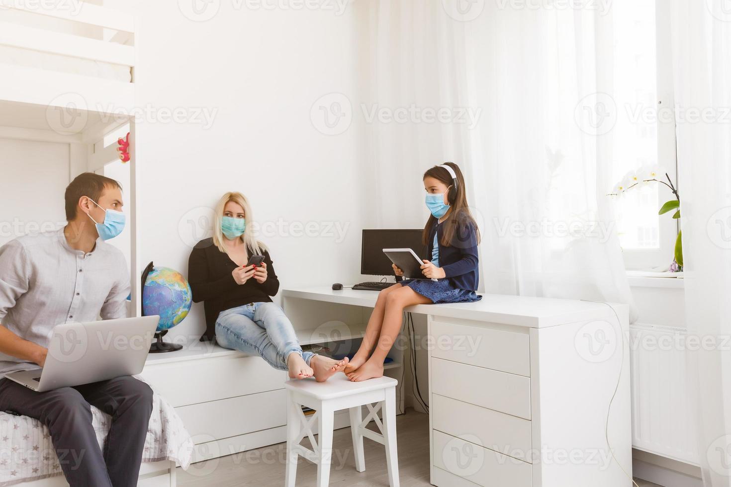 Young modern quarantined coronavirus family in medical masks. stay home stop the pandemic. Self-isolation together is the solution. Care covid-19. mom dad daughter millennials photo