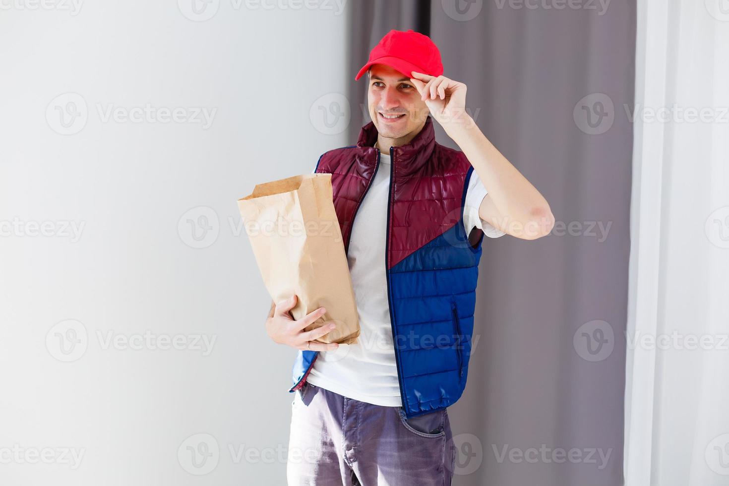 Paper pocket and food containers in hands of a smiling deliveryman. Quality service of a restaurant. photo