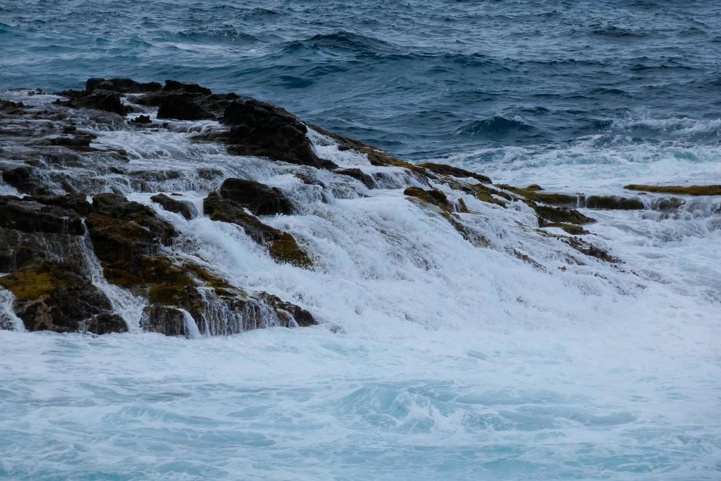 Large waves crashing against the rocks in the ocean photo