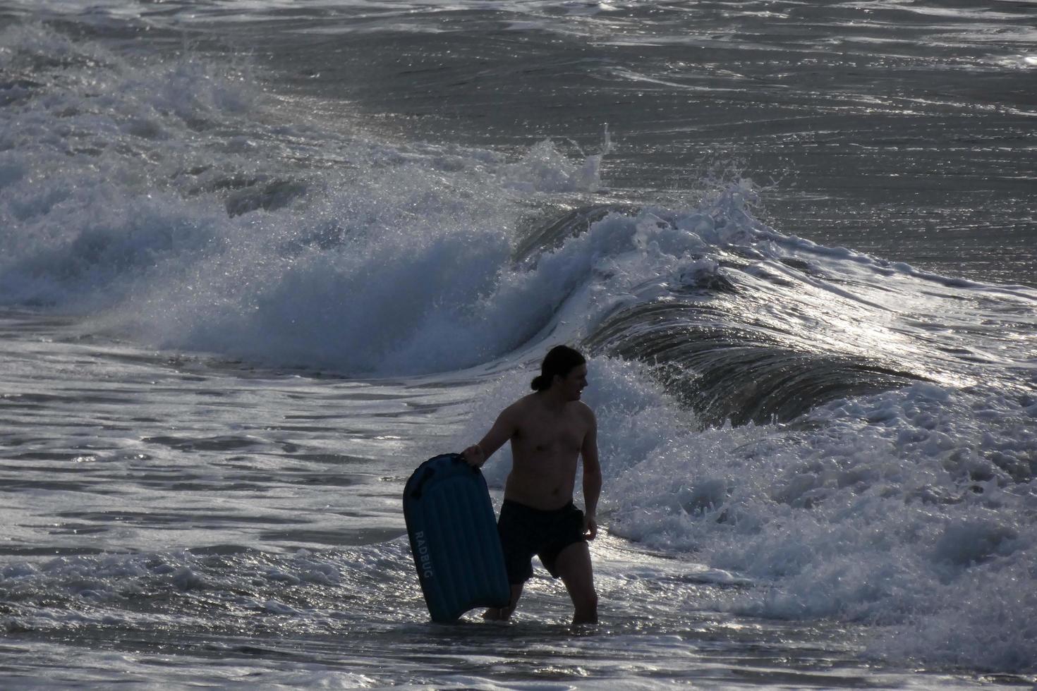 Surfers getting ready to enter the water and walking with the board along the shore. photo