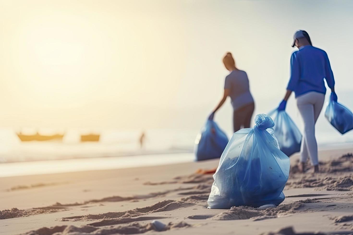 a group of unrecognizable people collecting garbage from the beach in blue bags for the problem of plastic pollution in the environment photo