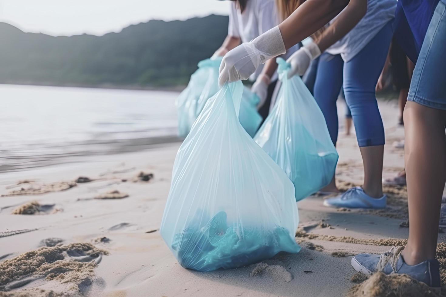 a group of unrecognizable people collecting garbage from the beach in blue bags for the problem of plastic pollution in the environment photo