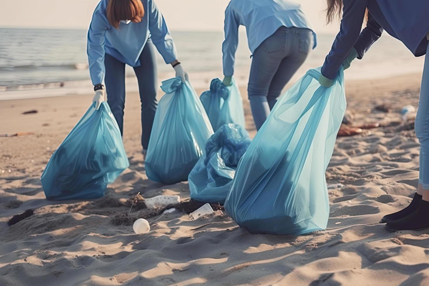 a group of unrecognizable people collecting garbage from the beach in blue bags for the problem of plastic pollution in the environment photo