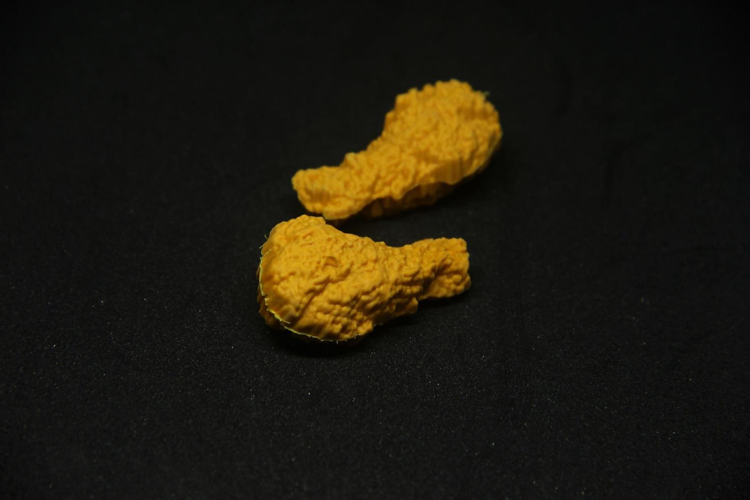 Yummy fried chicken shaped eraser. School or office stationary tool supplies with crispy fried oily junk food shape . isolated photo on dark black background.