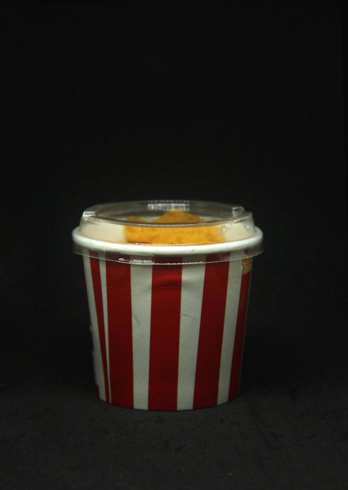 Pop corn paper bucket shaped eraser. School or office stationary tool supplies with red and white patterned cup shape. isolated photo on dark black background.