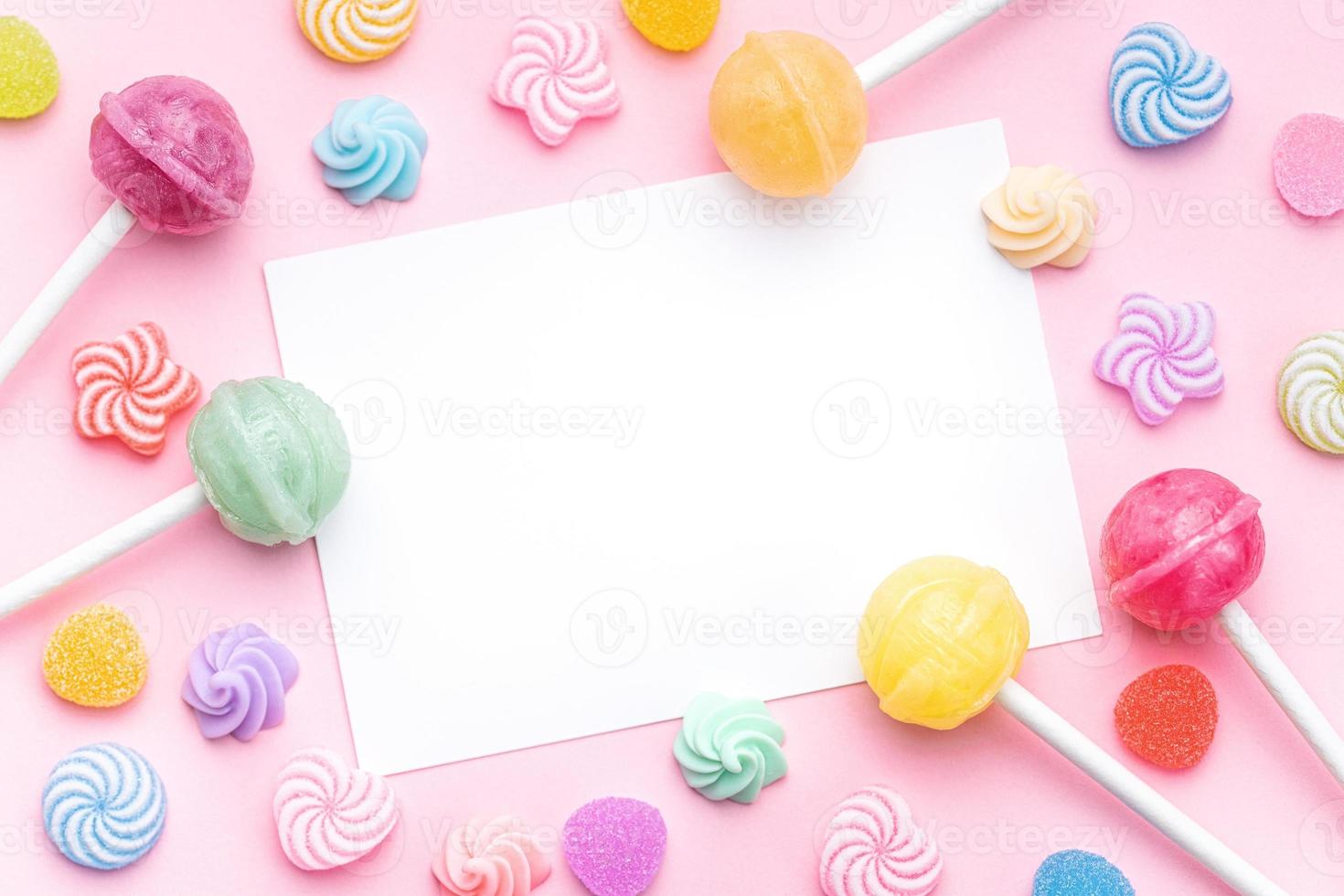 Sweet lollipops and candies and blank greeting card on pink background photo