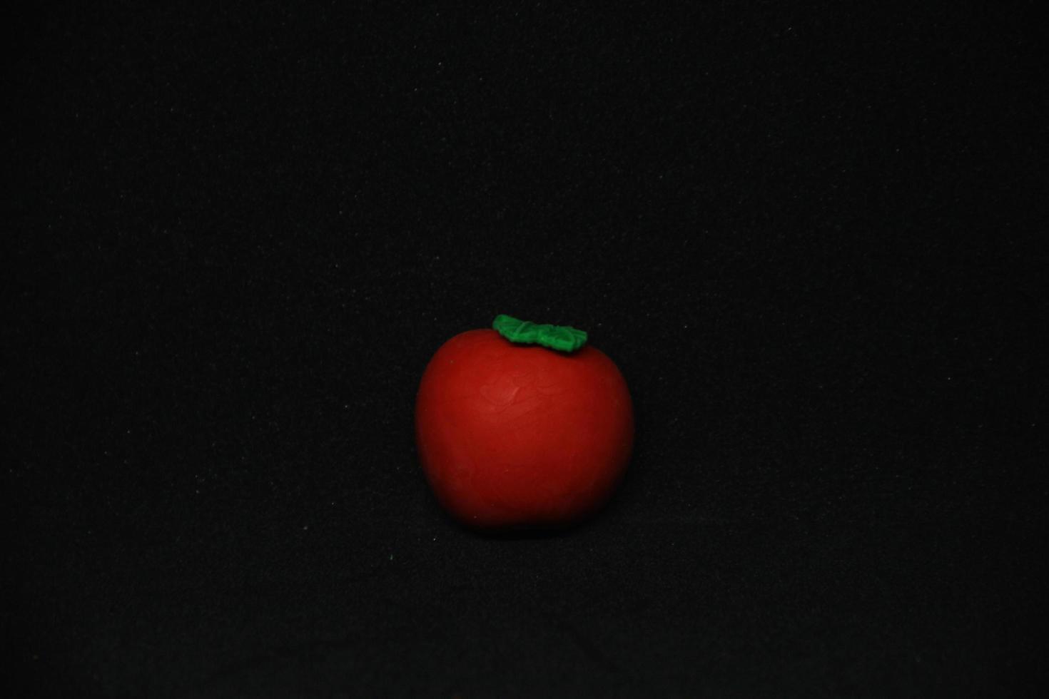 Round tomato shaped eraser stationary tools for office or school supplies. Isolated photo on plain dark black background.