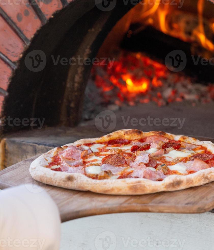 Chef placing pizza in brick oven photo