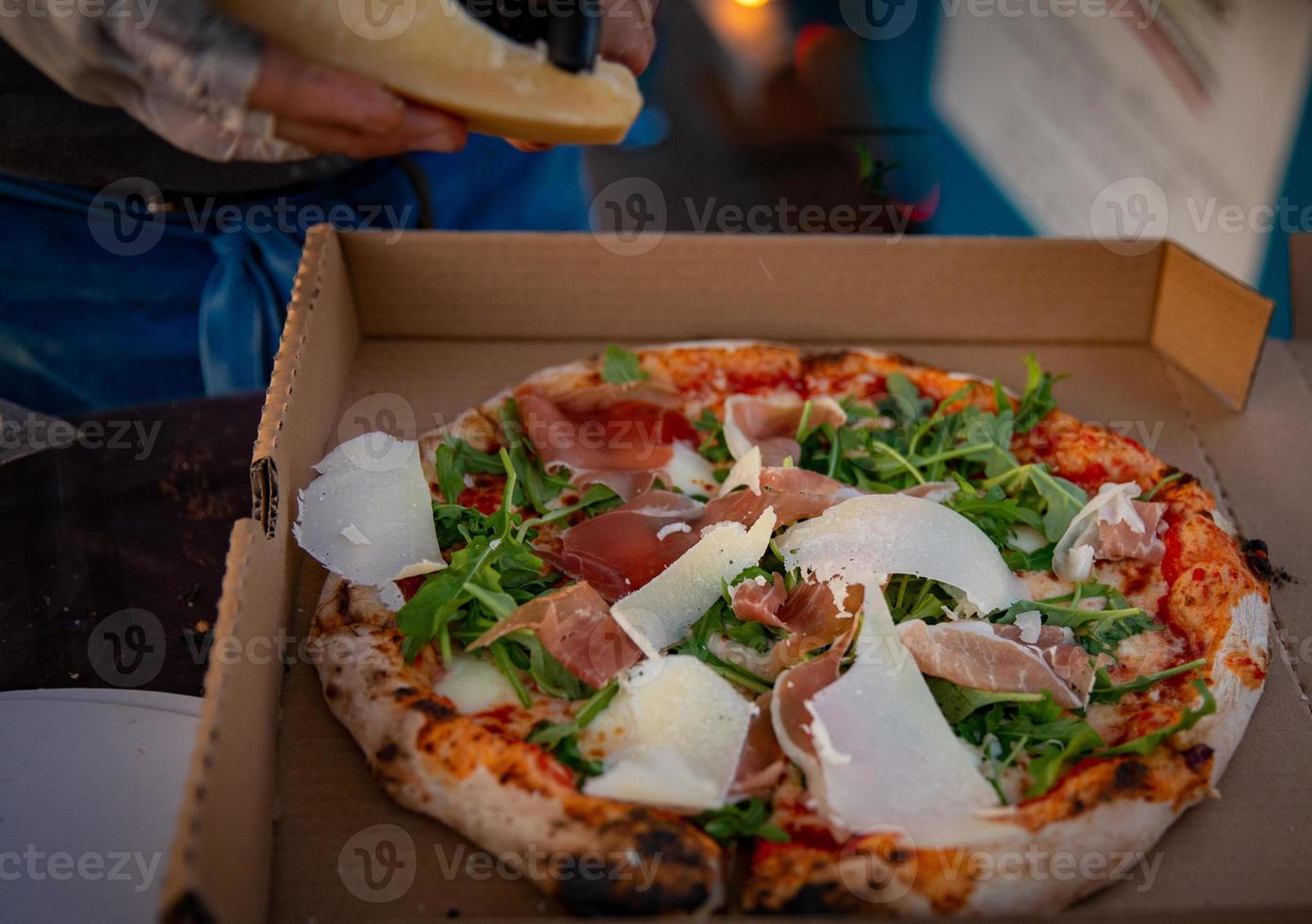 Carving fresh parmesan on a pizza photo