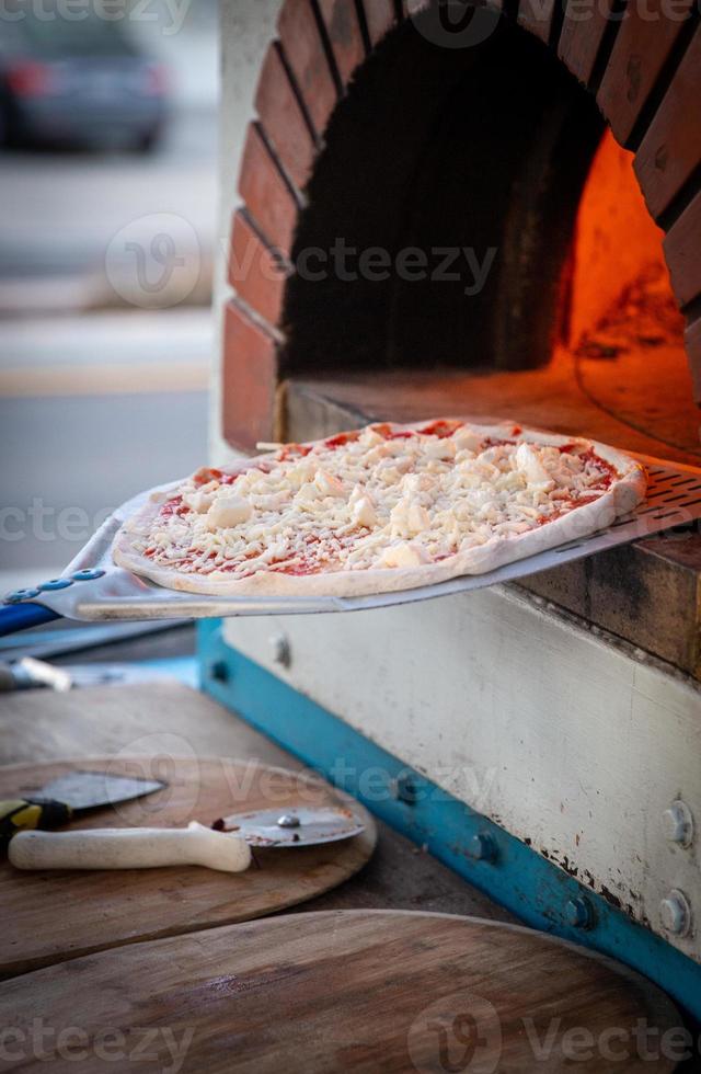 Placing pizza into brick oven photo