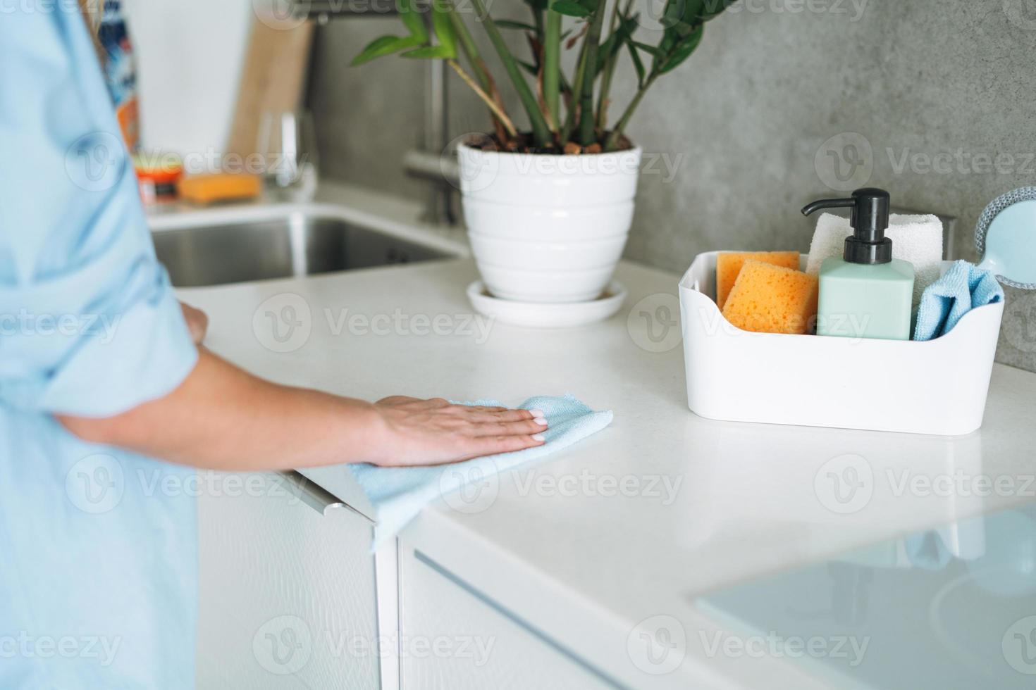 Box with things for cleaning kitchen on background of young woman at home photo