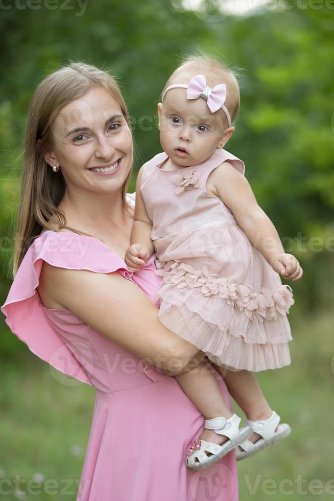 Happy woman holds one-year-old daughter in her arms. Motherhood. photo