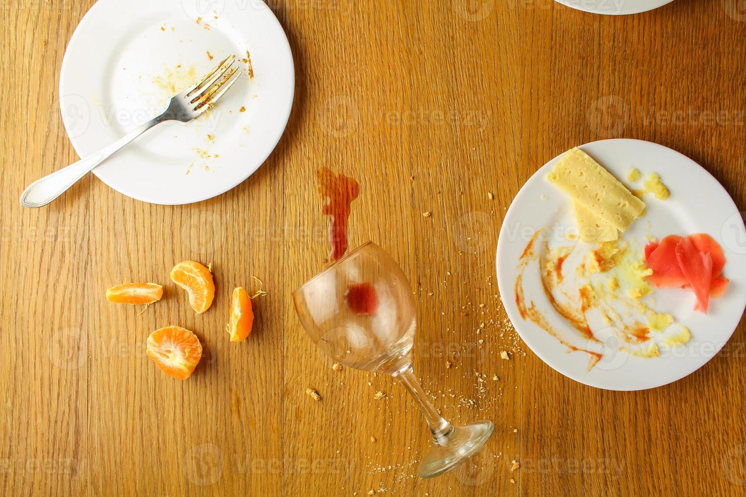 Messy table after party. Leftover food, spilled drinks, dirty dishes. photo